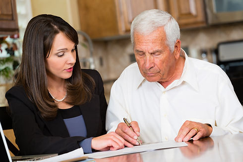 A young financial adviser helps an elderly man review paperwork