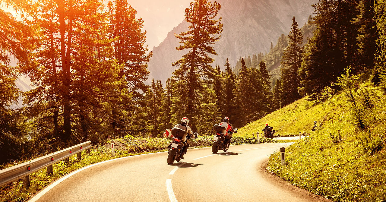 Group of motorcyclists riding on curves mountainous road, race of motorbike in Alps, beaut