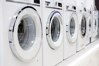 A row of white washing machines on display