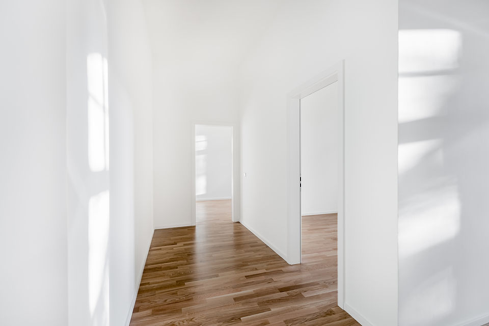 Bright, minimalist hallway with white walls and wooden floors