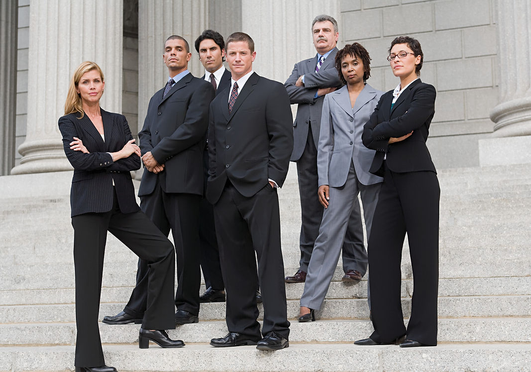 Group of corporate professionals in business attire posing confidently on outdoor stone steps.