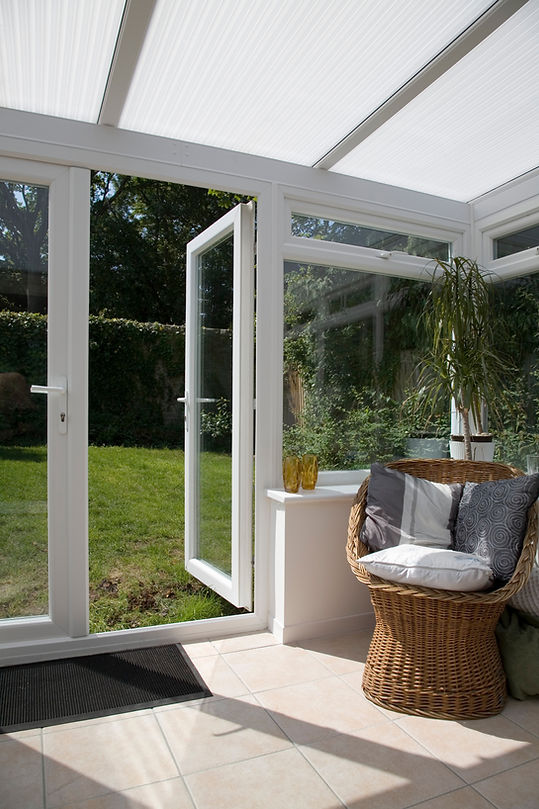 Open white French doors leading from conservatory out to garden