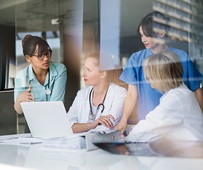 A photo of female doctors discussing at laptop desk. Multi-ethnic professionals are workin