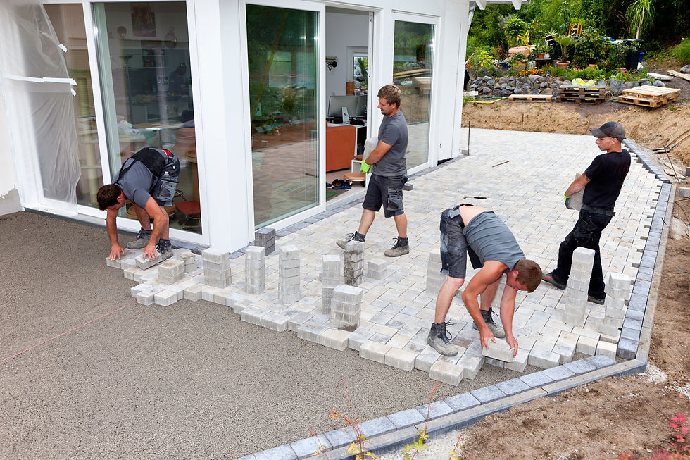 Professional team laying paved patio slabs along the exterior of a home