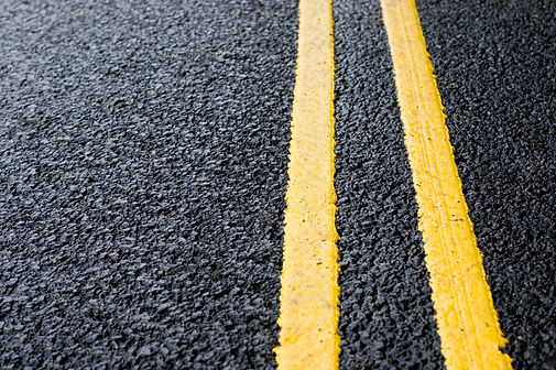 Close-up on yellow lines painted on fresh black tarmac