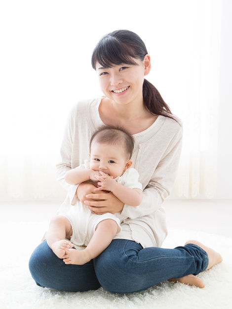 Smiling mother holding a baby on her lap, both looking at the camera, family photography
