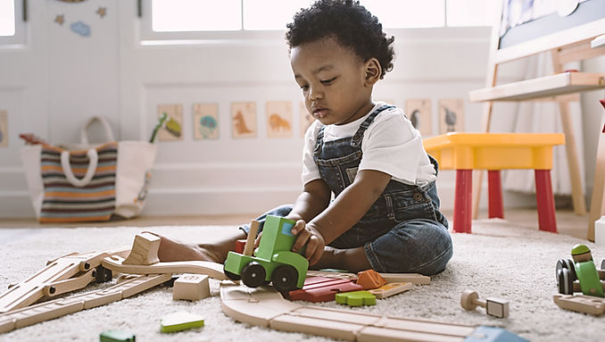 Litet barn som leker koncentrerat med leksaker på golvet
