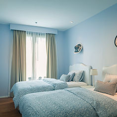 A tranquil bedroom featuring light blue walls and two neatly made beds