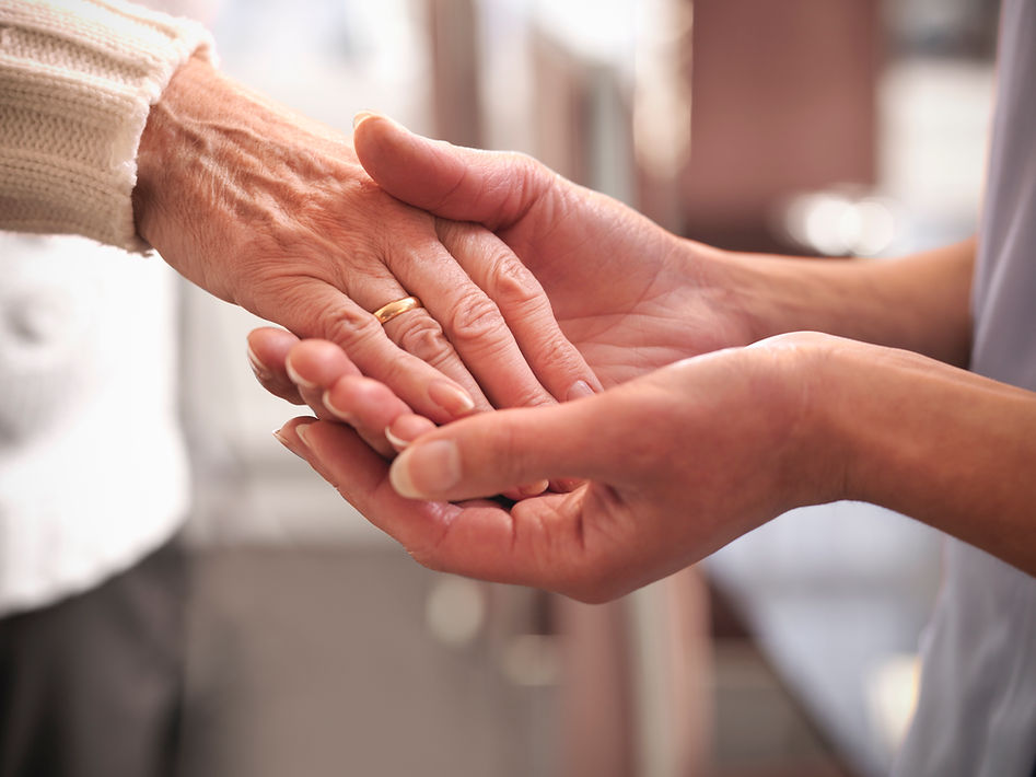 Two hands gently hold an older hand, symbolizing care and support