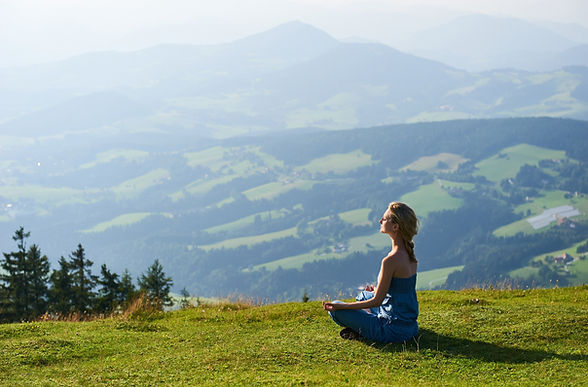 Mujer meditando en un prado alpino