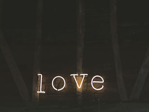 Neon glow spelling 'love' illuminates the rustic wooden backdrop, creating a warm and cozy atmosphere.