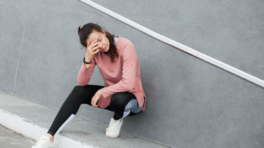 woman jogging and sitting at the side of the road