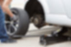 A man replacing the tyre of a white car