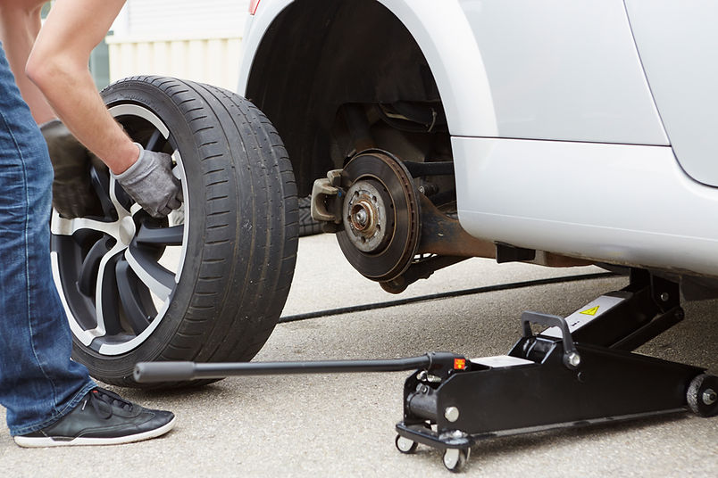 Car wheel removed during roadside tyre change using hydraulic trolley jack