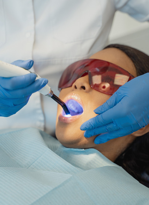 Patient receives dental treatment with a blue curing light.