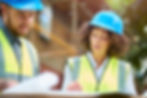 a female architect stands on a building site housing development and instructs a co -worker