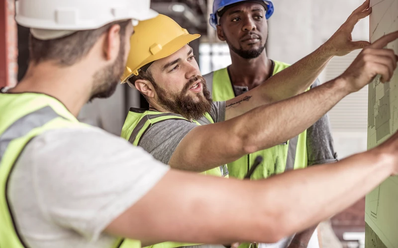 Workers in safety helmets and vests reviewing site safety procedures, representing control owner responsibilities in risk management