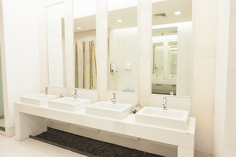Modern public restroom with four white sinks lined in a row