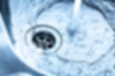 Close up of a Stainless steel kitchen sink with running water. The faucet is turned right