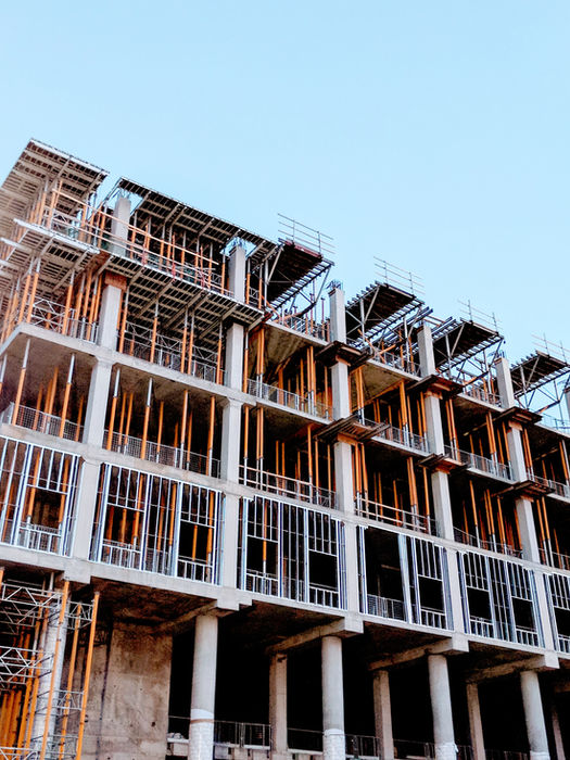 Low-angle view of a multi-story building under construction with wood and concrete framing.