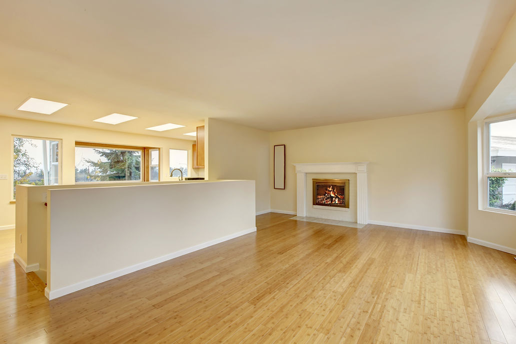 Empty living room interior featuring polished hardwood floor and a built-in fireplace with cream walls
