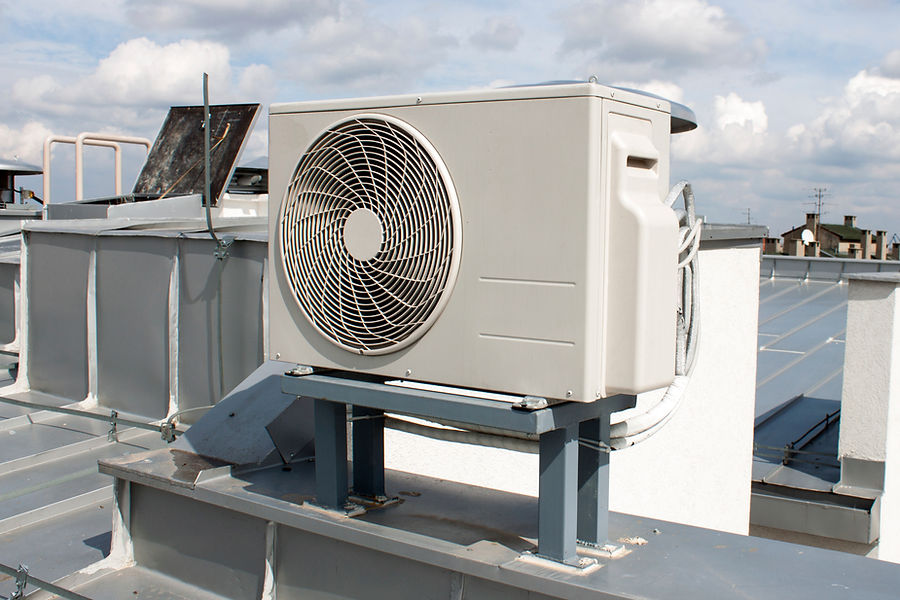 Rooftop air conditioning unit on metal supports, set against a clear sky with scattered clouds