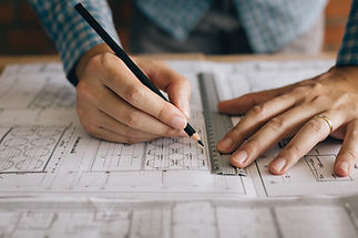 A Person drafting architectural plans with pencil and ruler