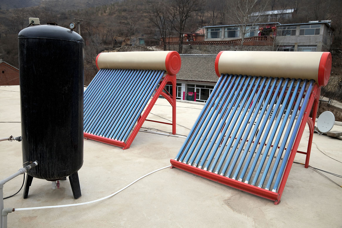 Two solar water heaters with blue tubes are on a rooftop