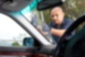 A man in a blue shirt replacing the glass of a car