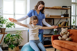 Female physical therapist working with young girl in home