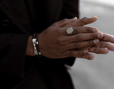 the image shows the two hands of one person rubbing on one another, in almost a prayer position. the person is wearing a silver ring and black leather bracelets.