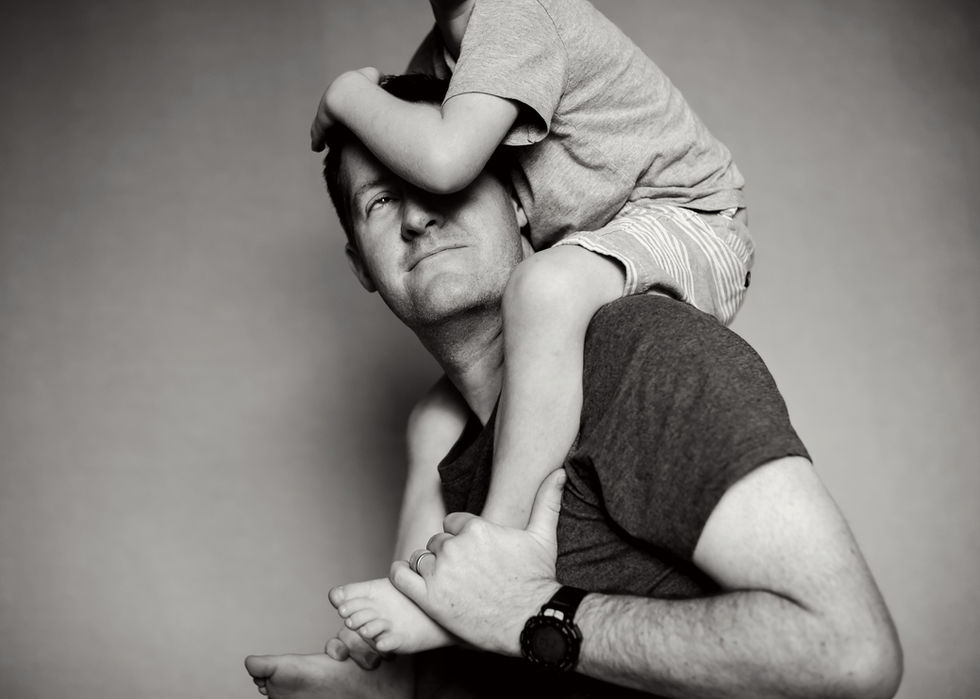 a man wearing a watch is carrying a child on his shoulders