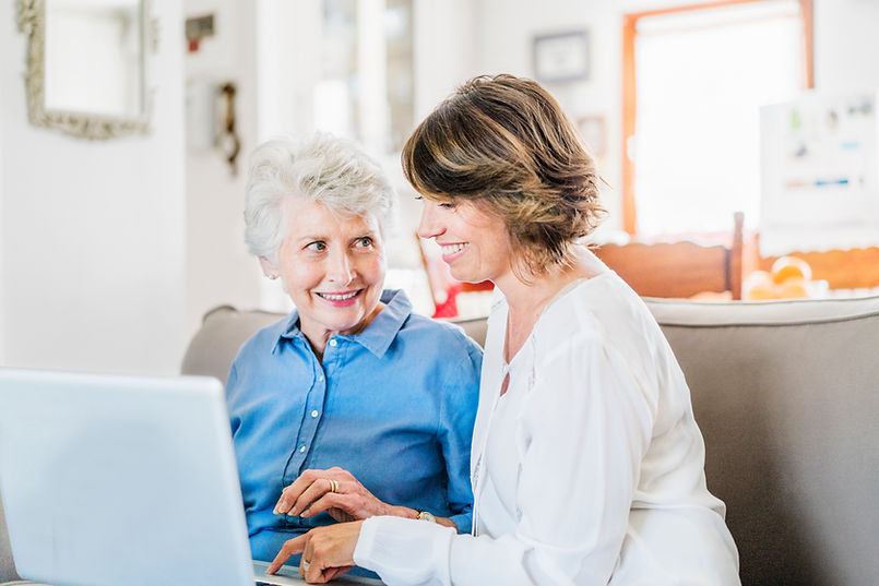 Two women sitting on a couch smiling at each other