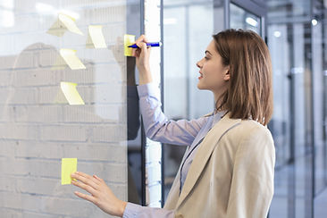 Persoanlberaterin für Handswerksbetriebe beschriftet Post-Its und klebt sie auf eine Tafel