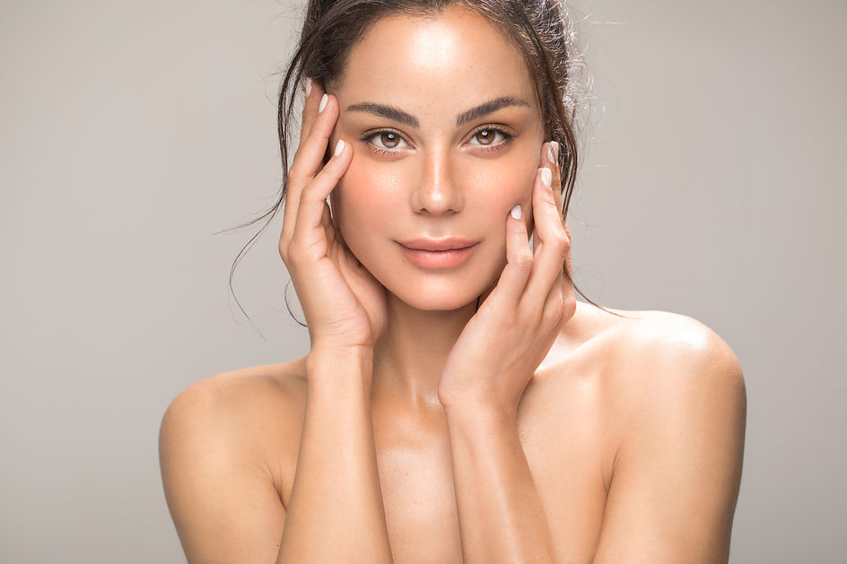Close up studio shot of a beautiful brunette woman with glowing skin