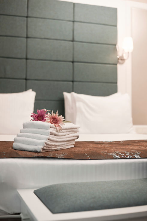Luxury stay hotel room featuring a dark grey tufted headboard white pillows and a brown bed runner