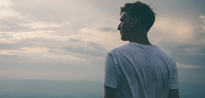 Un homme pensif regardant au loin vers l'horizon pour illustrer le besoin profond de transformation intérieur