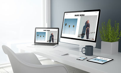 Bild von einem Schreibtisch, zu sehen ein Handy, ein Monitor und ein Laptop