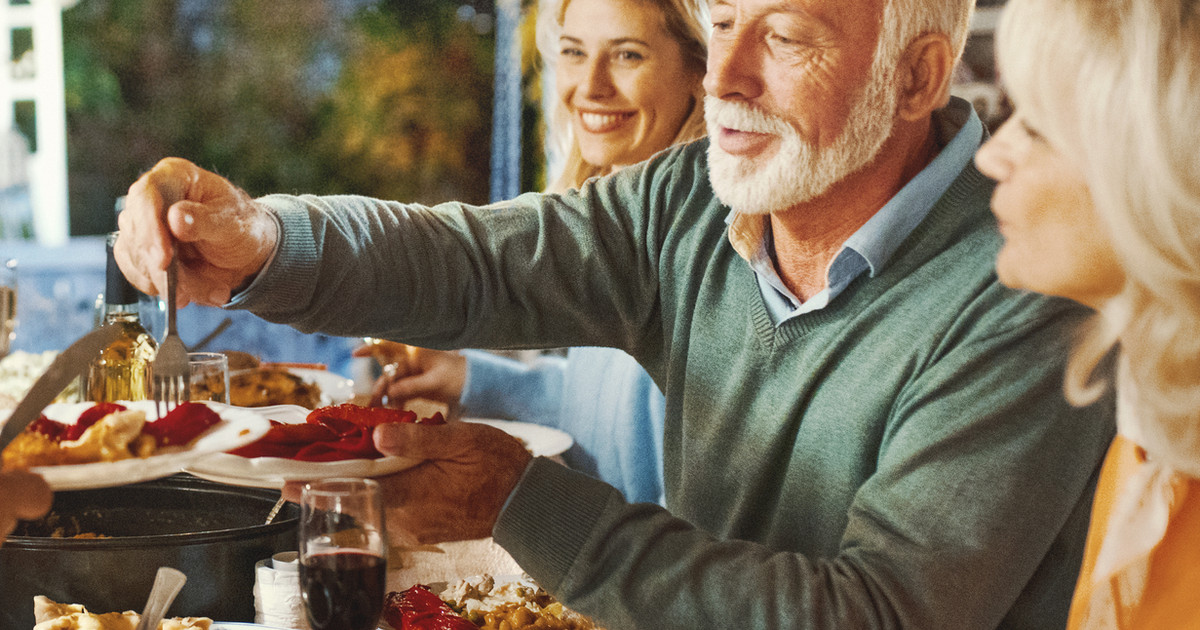 A person laughing with family around a table outdoors, pain not visible or implied, conveying everyday connection and life.