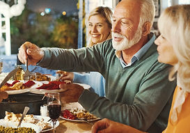 A person laughing with family around a table outdoors, pain not visible or implied, conveying everyday connection and life.