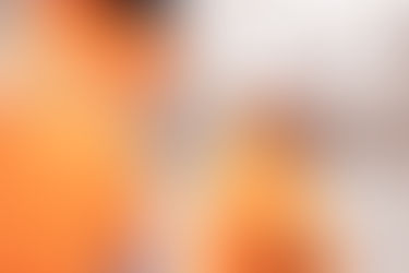 Smiling woman in orange jacket.