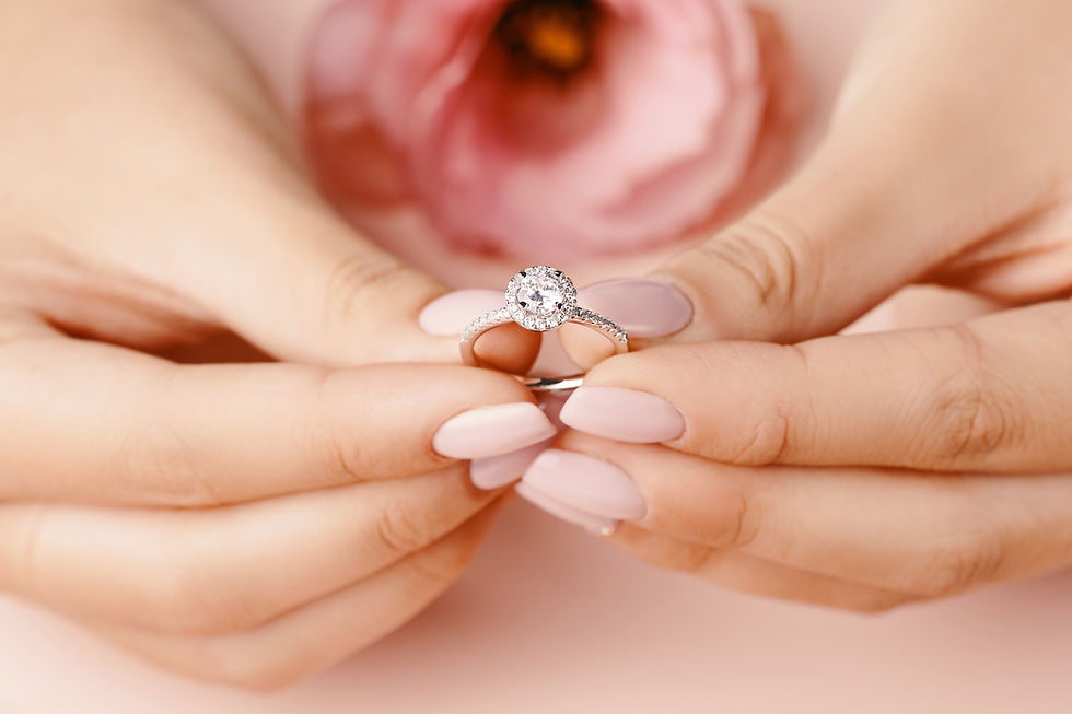 Hands holding a diamond ring, pink flower background