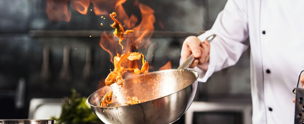 Chef flips food in pan; Culinary experience with tomatoes in the background