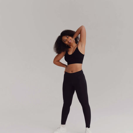 A woman in black active wear smiling and stretching