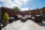 A general view of a sun terrace patio with brown rattan garden corner sofa and armchairs,