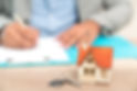 House model and keys with person signing documents in the background