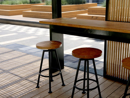 Outdoor bar seating on a pool deck with wooden stools