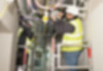 Two electricians are repairing electrical wiring in an industrial hallway