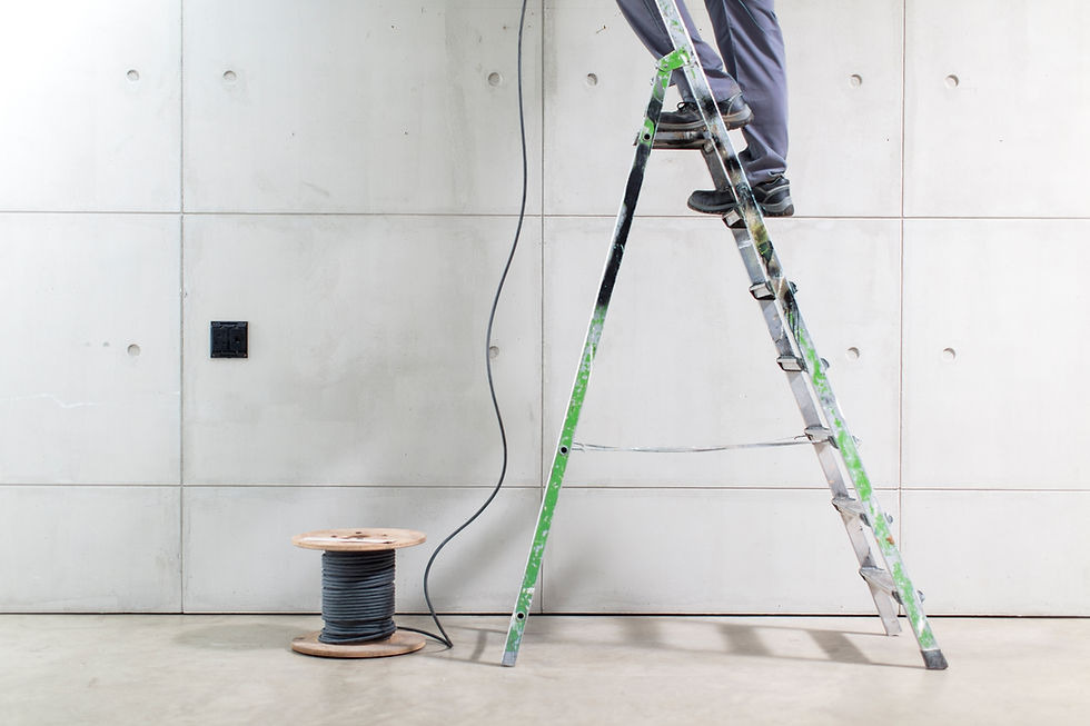 The image shows a worker on a ladder during an electrical installation