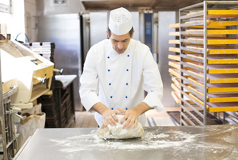 Baker kneading dough in a bakehouse or bakery